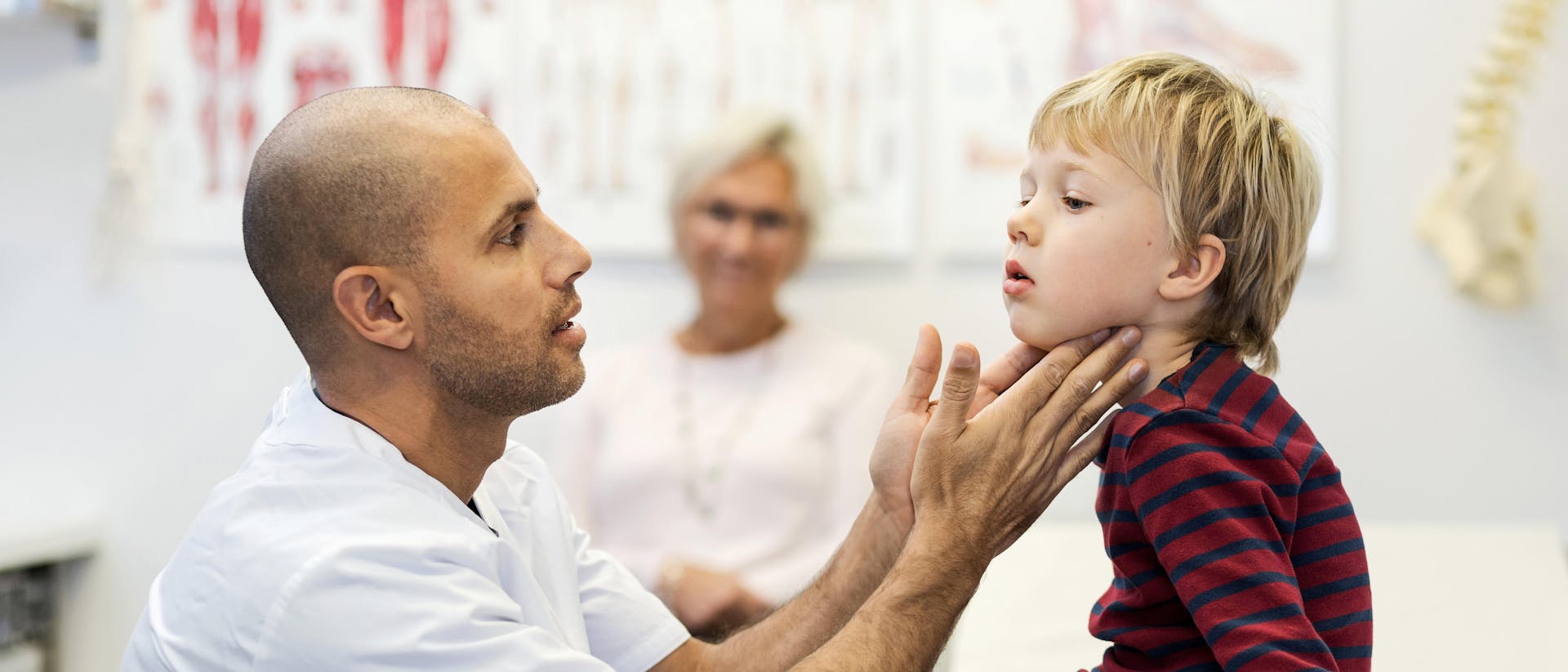 Male doctor checking boys throat at clinic 551423613.jpg