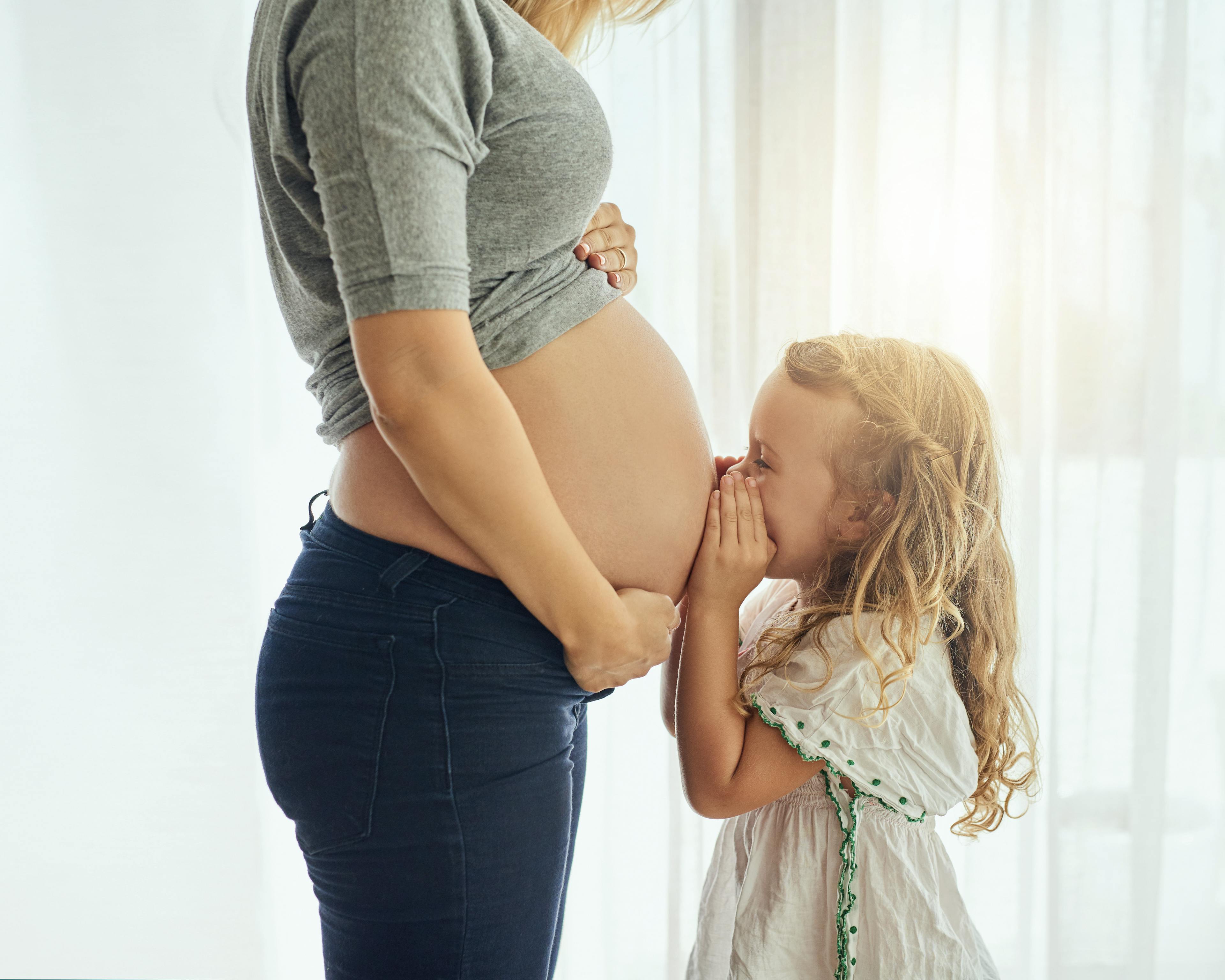 Little girl kissing mums pregnant tummy